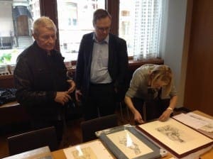 Durk Dehner, president ToFF; Kimmo Antila,  director Postal Museum, Susanna Luoto, representative, ToFF going  over Tom of Finland artwork for display.