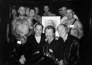 (seated L to R) John Waters, Durk Dehner anf Greg Gorman with men at the TOM House in front of Robert Maplwthorp's portrait of TOM.